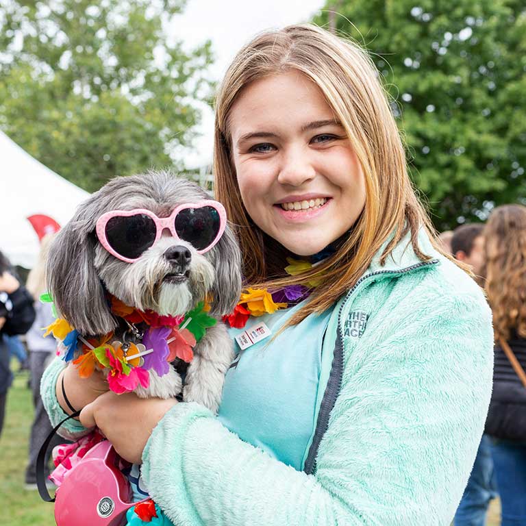 A girl poses with her dog that's dressed up in sunglasses and a lei for the Regatta dog costume contest.