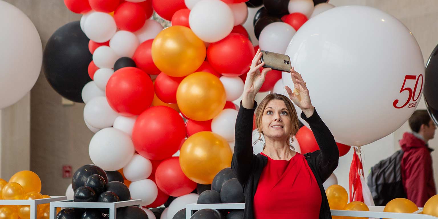A woman takes a selfie with a balloon display.