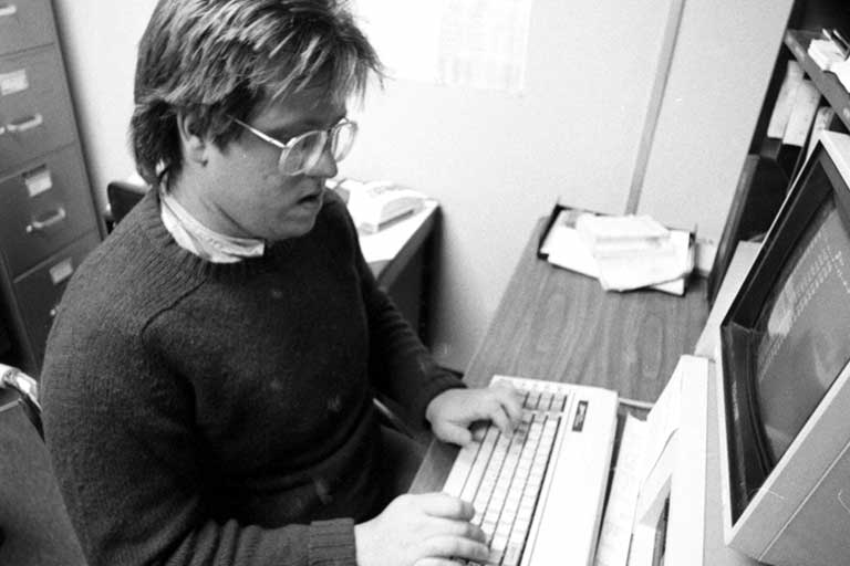 A reporter for the Sagamore types at a computer. Black and white photo.